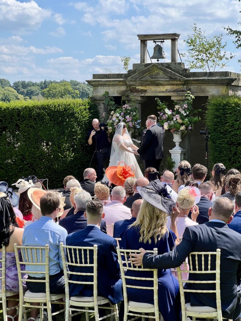 Wedding ceremony outside in the sunshine at Sandon hall