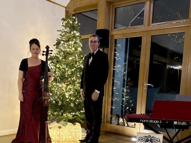 JAM Duo Jules and Anne-Marie by a Christmas Tree with A Nord Stage Piano in the foreground