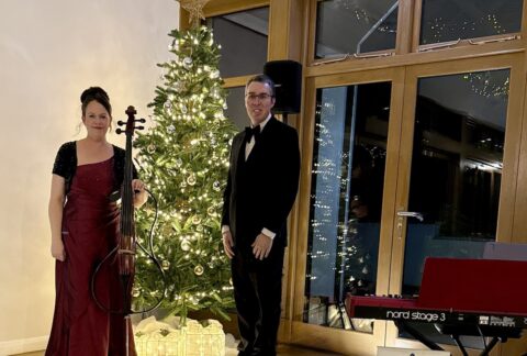 JAM Duo Cello and PIano Duo beside a Christmas Tree and Nord Stage 3 piano